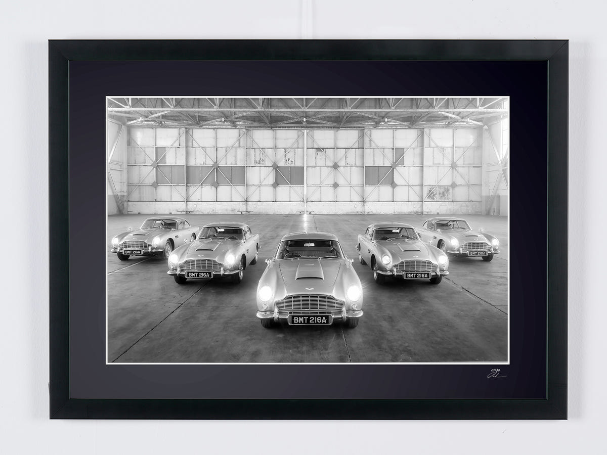Cinq Aston Martin DB5 alignées dans un hangar