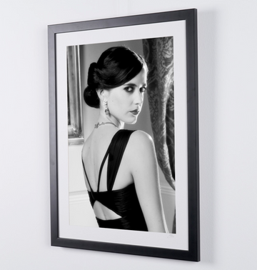 Eva Green in James Bond 007 : Casino Royale (2006), in een jurk met open rug en opgestoken haar, over haar schouder kijkend, ingelijste filmfoto in zwart-wit, lijst in perspectief van rechts.