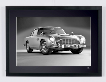 James Bond 007 : Goldfinger (1964) — Aston Martin DB5, coche de tres cuartos delantero sobre fondo liso, con matrícula FMP 7B visible, fotografía de cine enmarcada en blanco y negro, vista frontal del marco.
