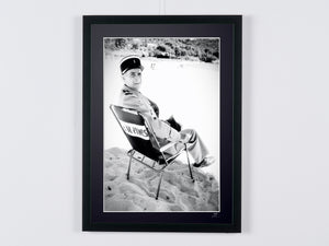 Le Gendarme et les Extra-terrestres (1979) - Louis de Funès (Ludovic Cruchot), in his on-set chair on the beach (black and white) — framed cinema photograph