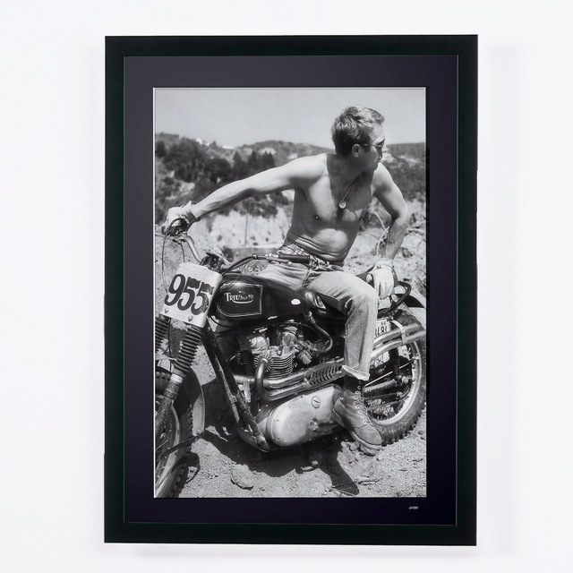 Steve McQueen in The Great Escape (1963), shirtless on a Triumph motorcycle numbered 955, framed cinema photograph in black and white.